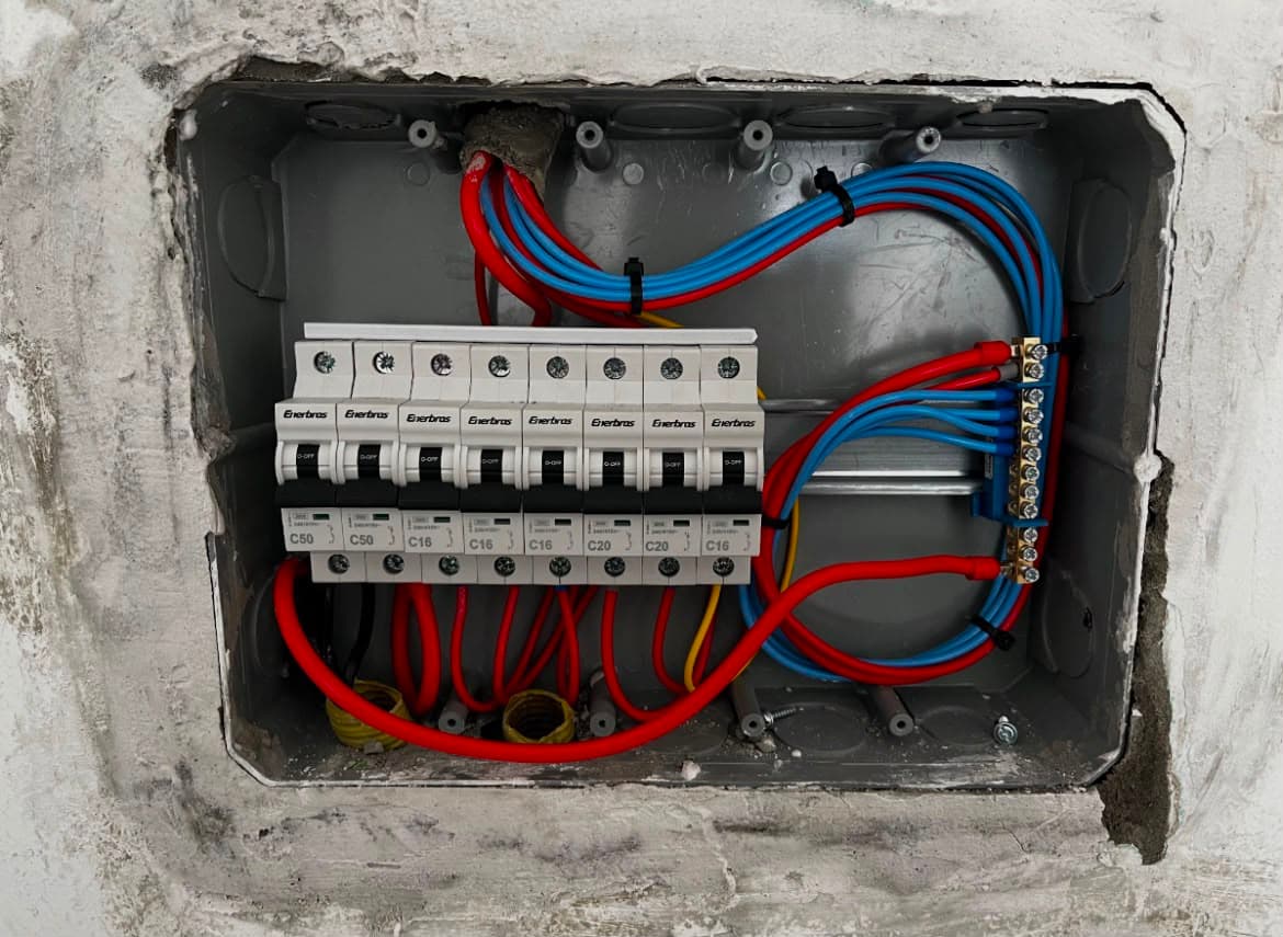 Quadro de disjuntores recém-instalado em nicho de alvenaria, fiação organizada